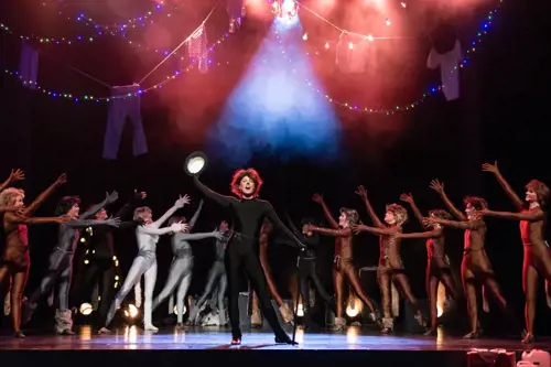 Studenter iført kattekostymer opptrer på scenen