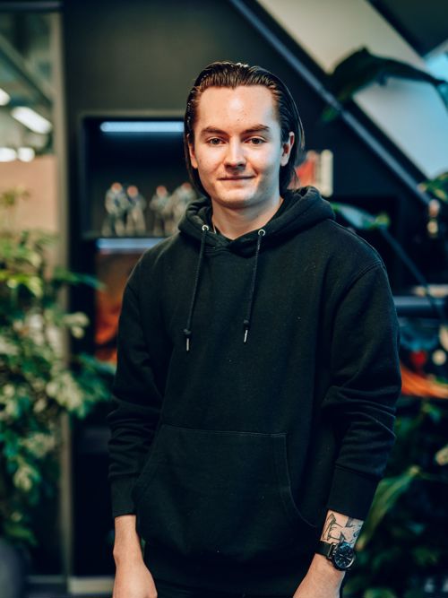 Mann i sort hettegenser smiler til kamera.