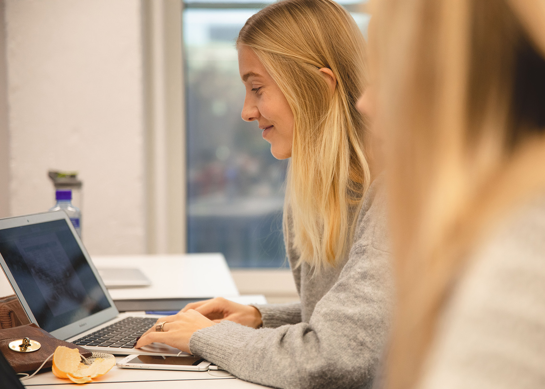 Bilde av ung kvinne med blondt hår som sitter foran en laptop.