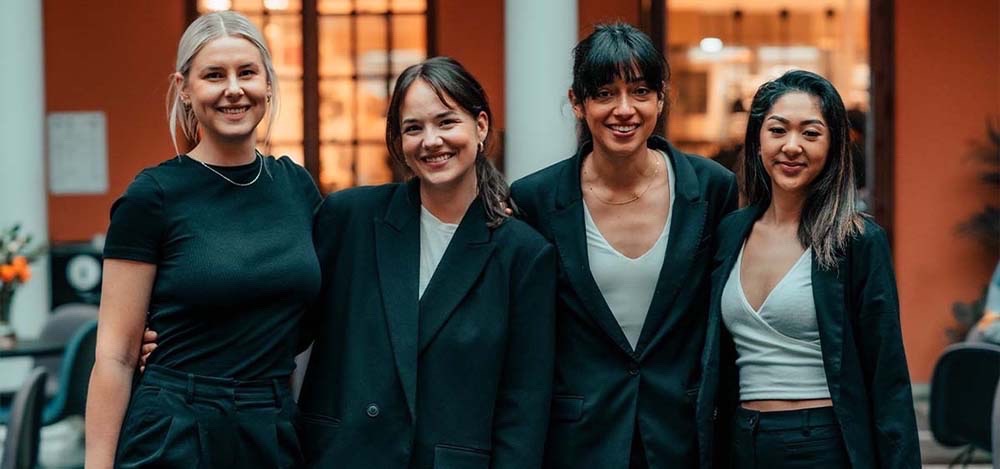 Fire kvinnelige studenter poserer for et bilde mens de smiler. Foto.