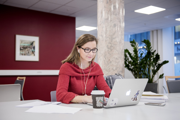 Foto av kvinne med laptop ved et møtebord.