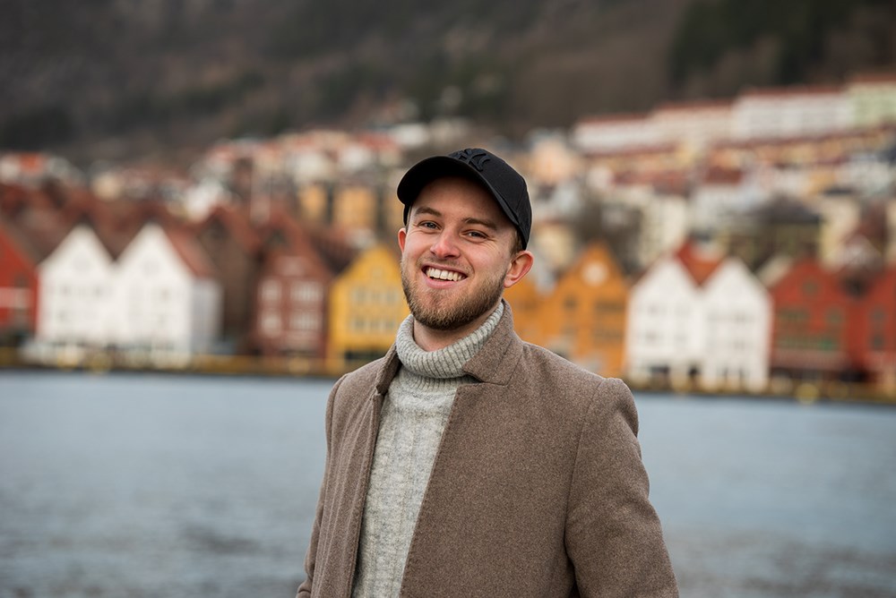 Foto av en smilende mann foran Bryggen i Bergen.
