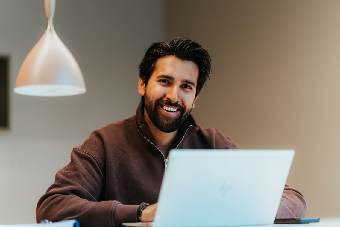 Nettstudent jobber med PC på kjøkkenbordet hjemme.