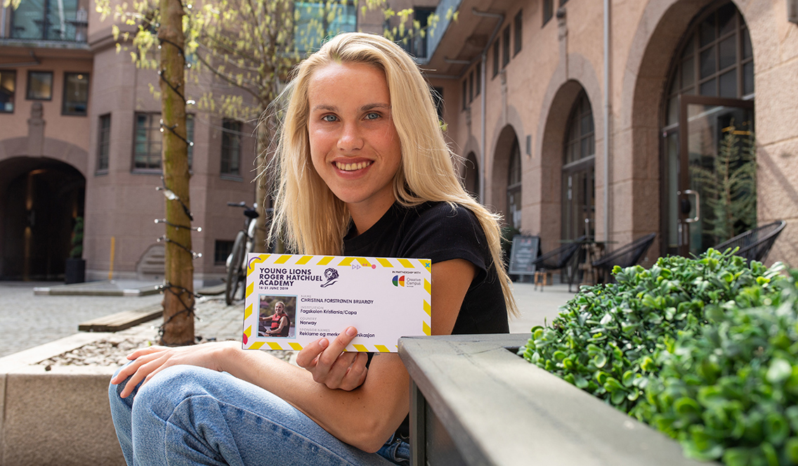 Smilende jente viser fram en billett til Cannes Lions som hun har vunnet