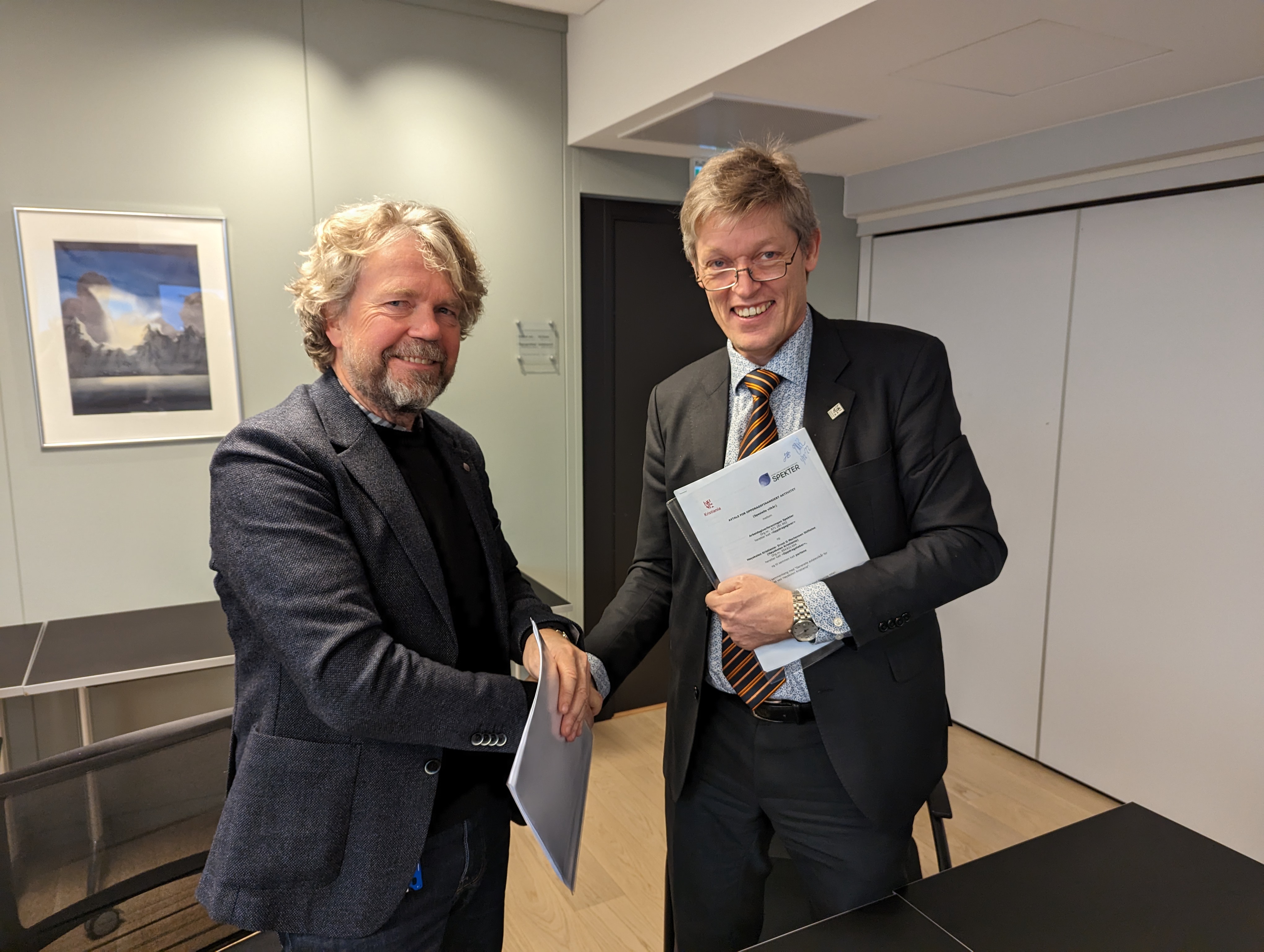 Olav Kvam, til venstre, og Jens Barland tar hverandre i hendene på et møterom hos Spekter etter å ha signert samarbeidsavtalen