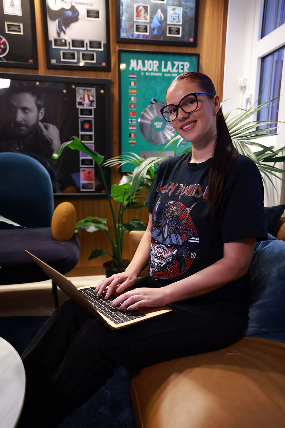 Foto av Camilla Sporsheim som sitter i en skinnsofa med Mac-en på fanget.