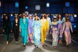 Flere modellergår mot kamera på en catwalk med flotte fargerike klær på seg