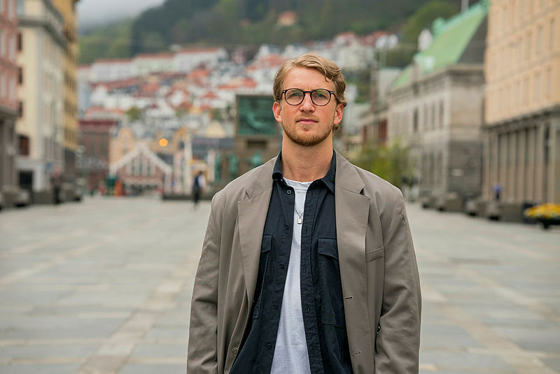 Foto av Vetle som står på Torgallmenningen i Bergen på en overskyet dag. 