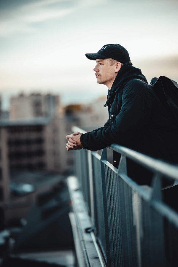 Bilde av ung mann med caps som lener seg over rekkverk.