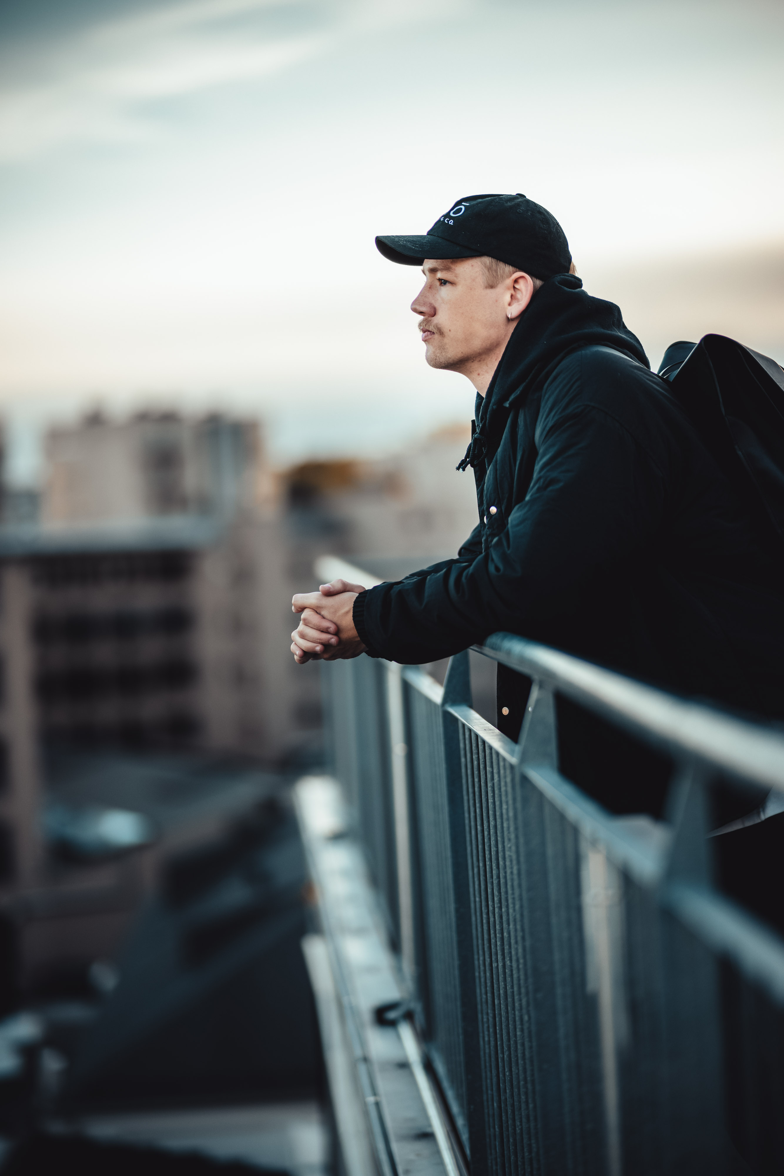 Bilde av ung mann med caps som lener seg over rekkverk.