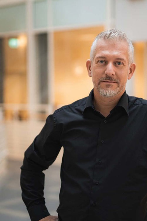 Foto av mann som ser i kamera og smiler..