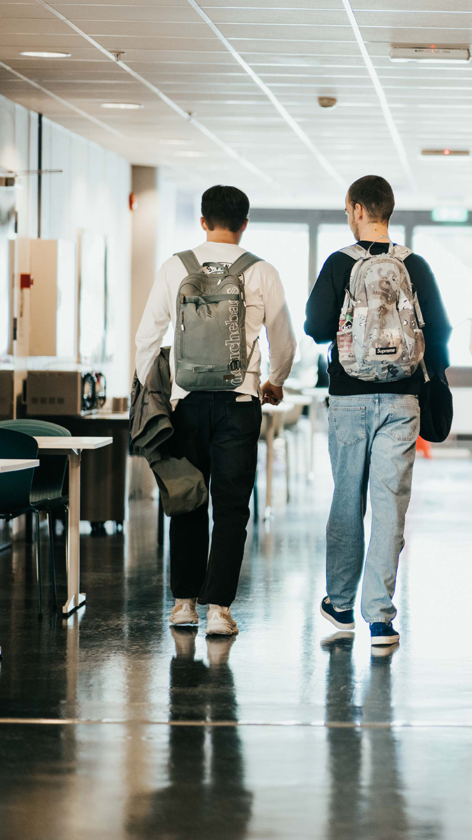 Foto bakfra av to mannlige studenter med ryggsekker