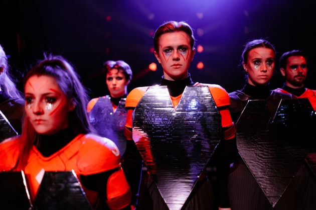 Skuespillere i futuristiske kostymer.