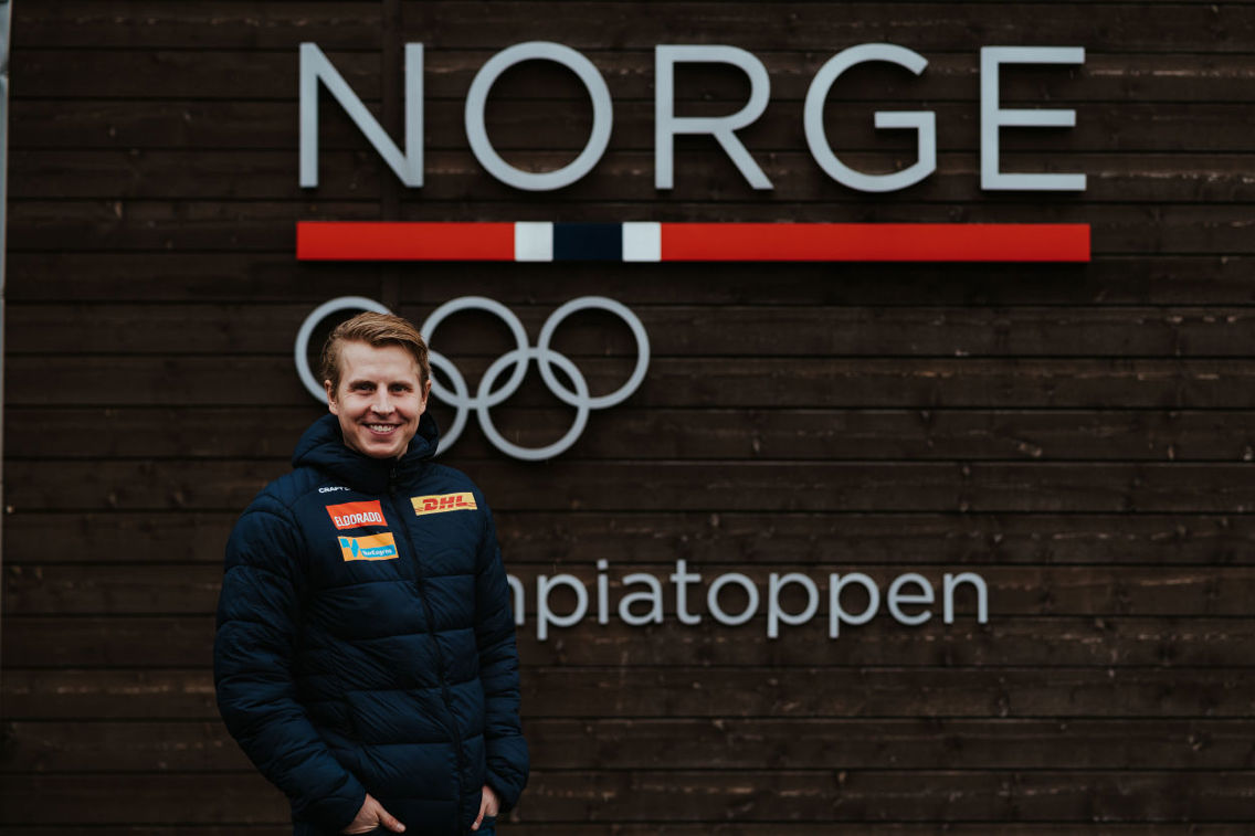 Simen Hegstad Krüger foran et Olympiatoppen-skilt.