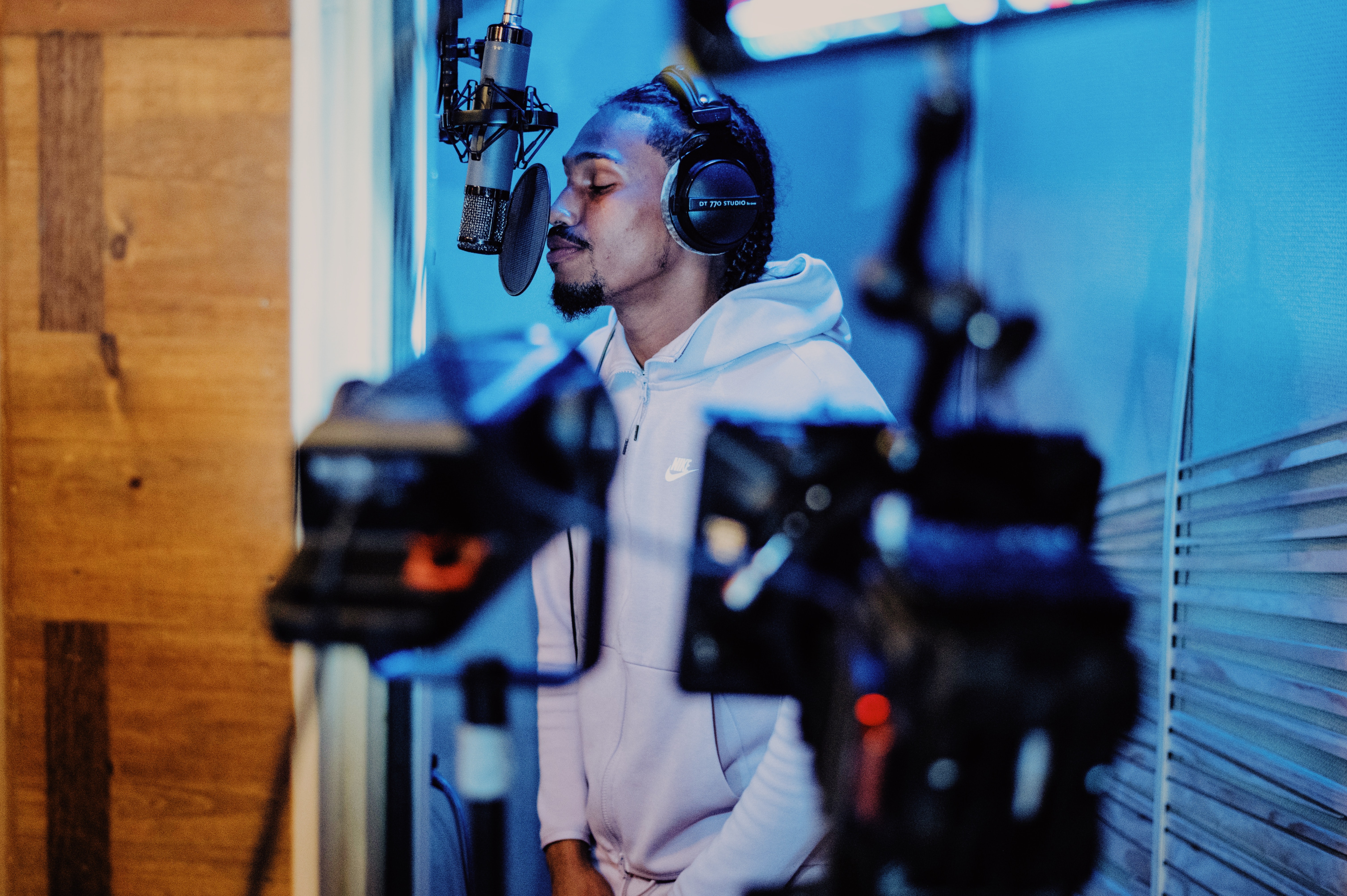En ung mann står i studio og synger. 