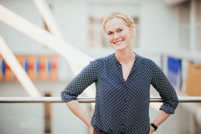 Dame i mønstret skjorte smiler.