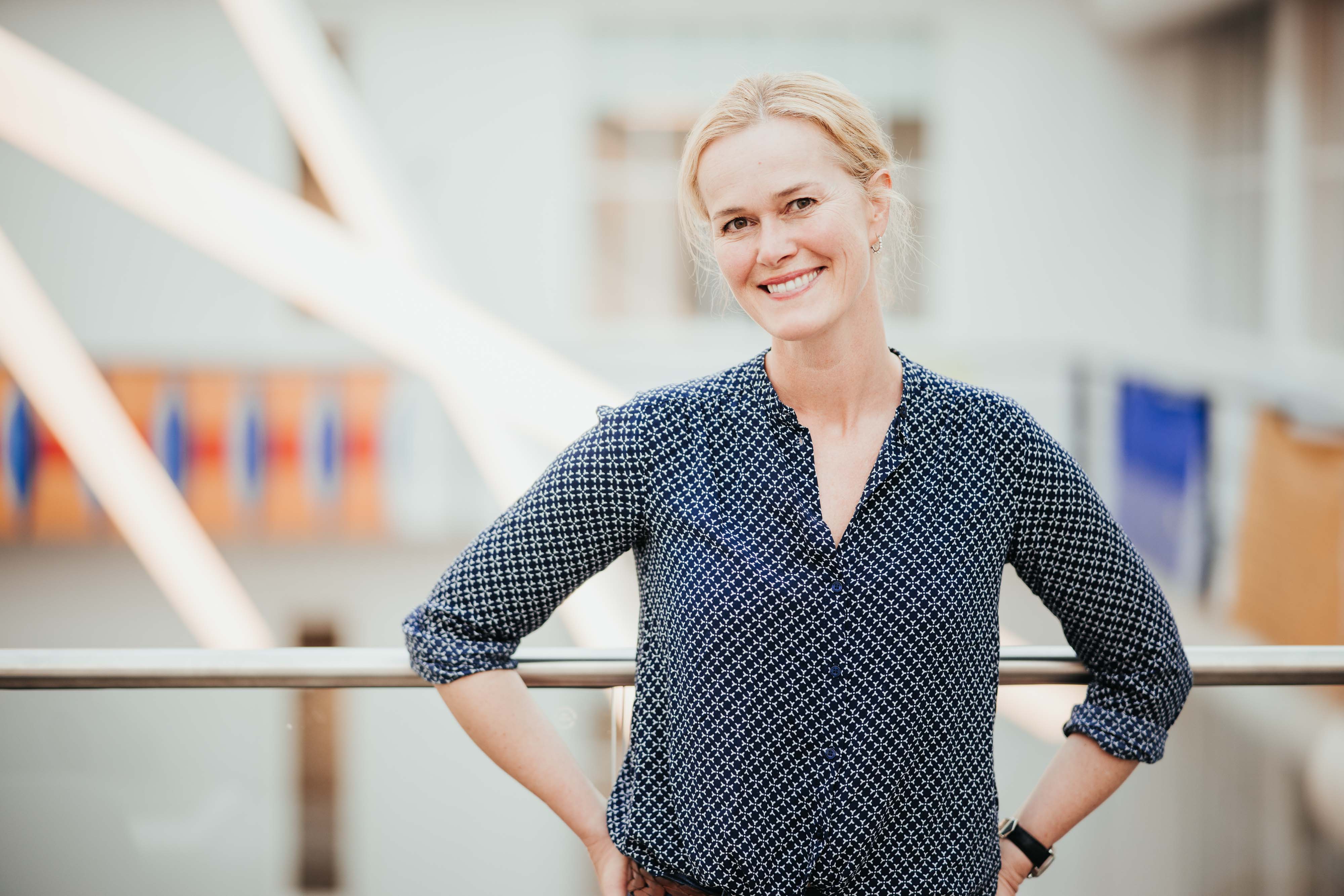 Dame i mønstret skjorte smiler.