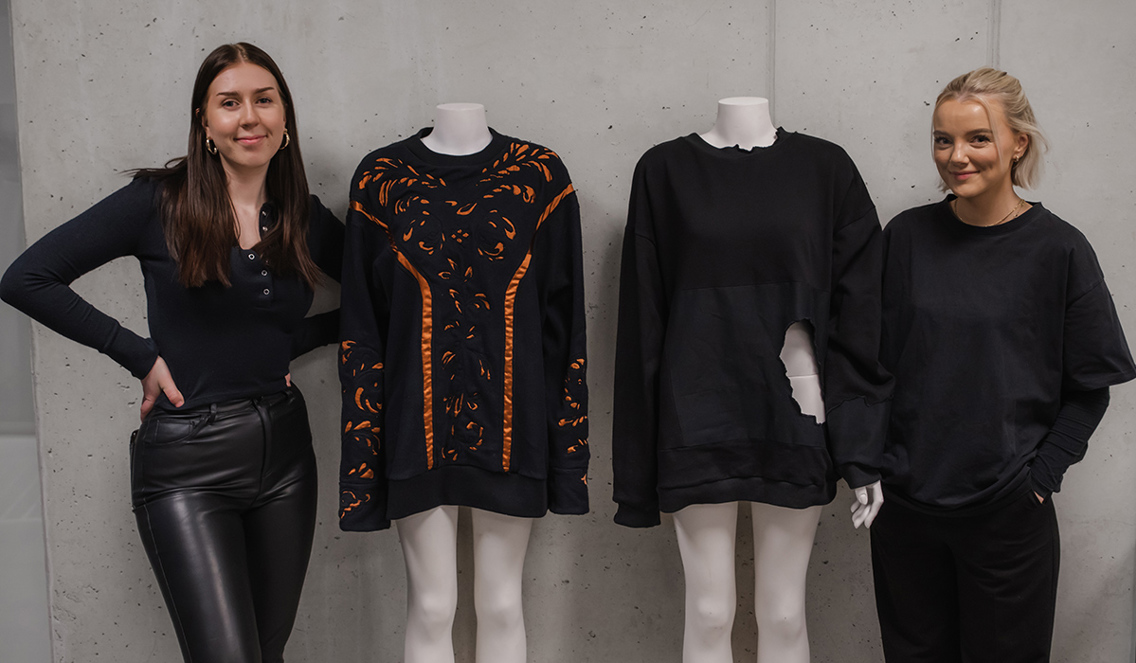 Foto av Celine Isnes og Julie Marthinsen som står ved siden av hver sin sømbyste med collegegenseren de har designet.