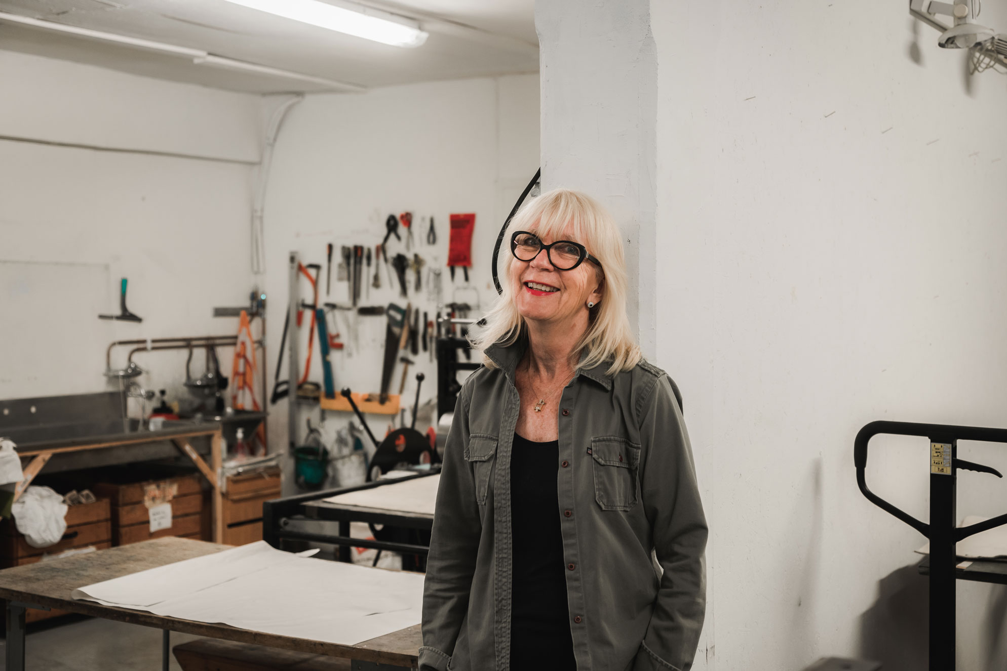 Bilde av Astrid som står i et verksted og smiler til kamera