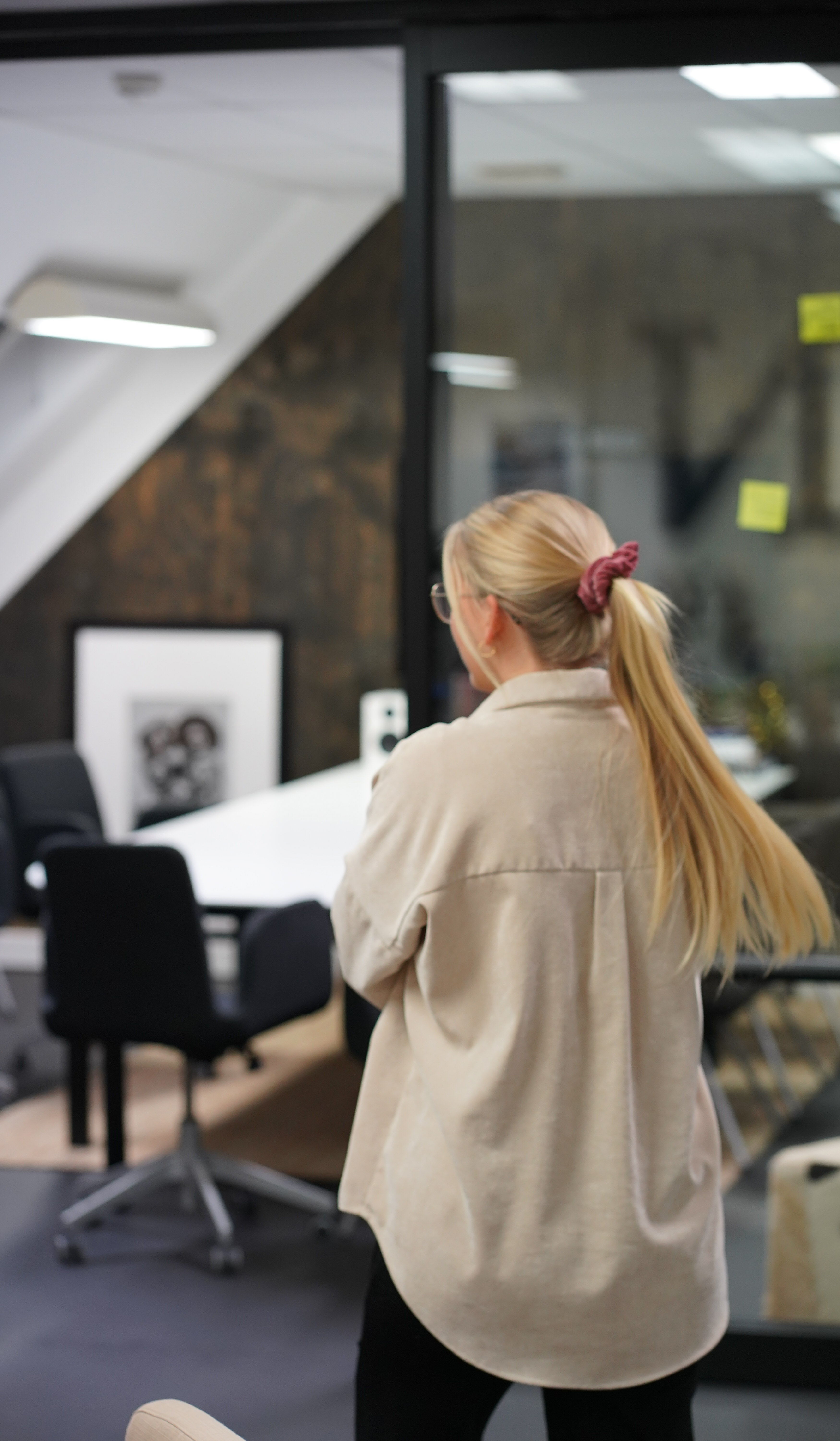 Eline Langøy Brattsli på kontoret til S & B-N der hun nylig har fått jobb. På bildet ser man baksiden av Eline, med en lang blond flette