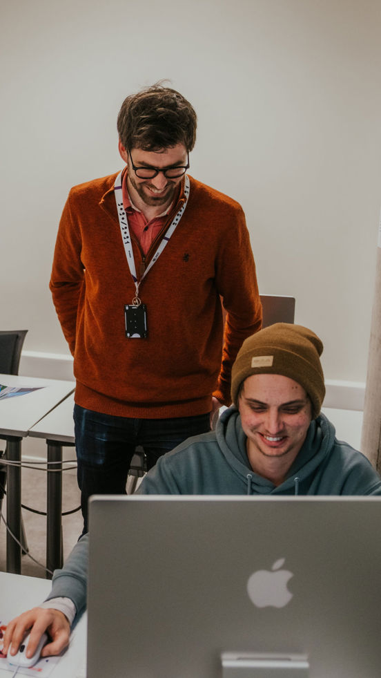 Student og faglærer ser på arbeid gjort på datamaskin. 