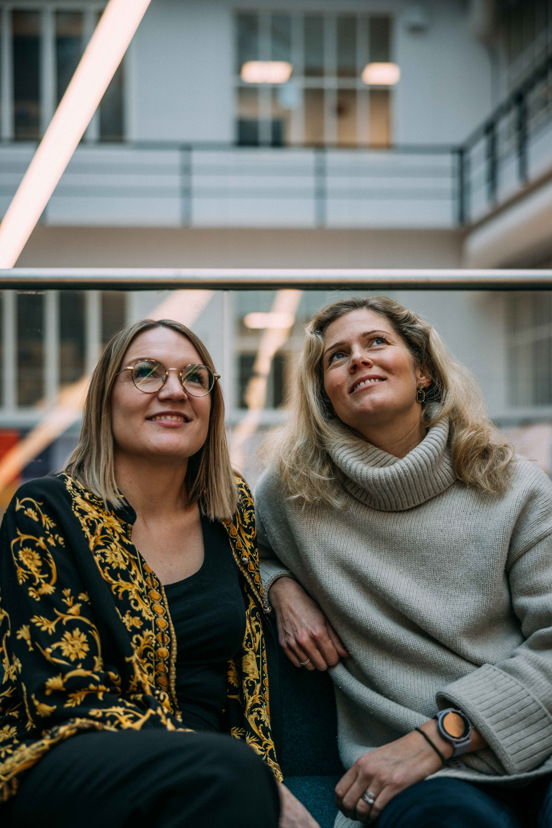Adeline og Christin sitter i en trapp.