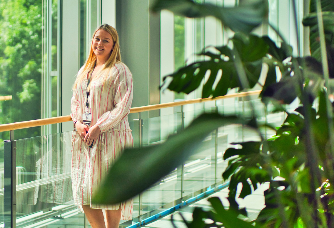 Foto av Benedikte Eliassen Fagerheim som står ved et vindu i et kontorbygg.