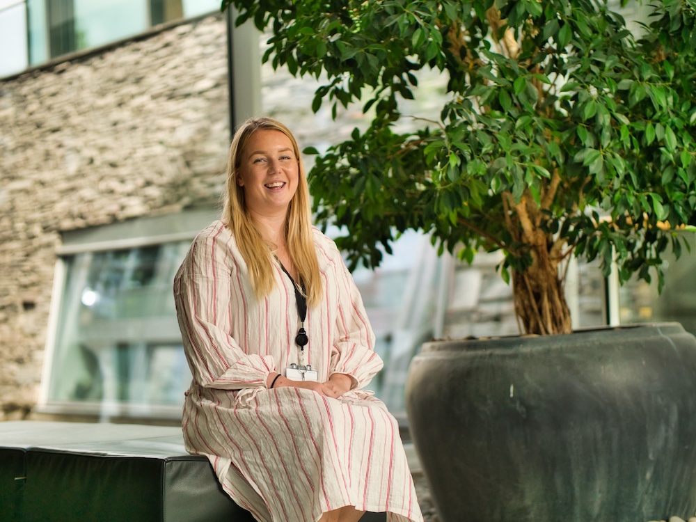 Foto av Benedikte Eliassen Fagerheim som sitter på en benk i en vinterhage.