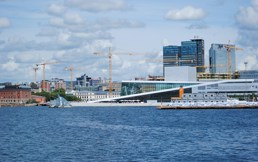 Et bilde av Oslo tatt fra Oslofjorden hvor du ser Operataket, postgirobygget, radisson-bygget og kraner