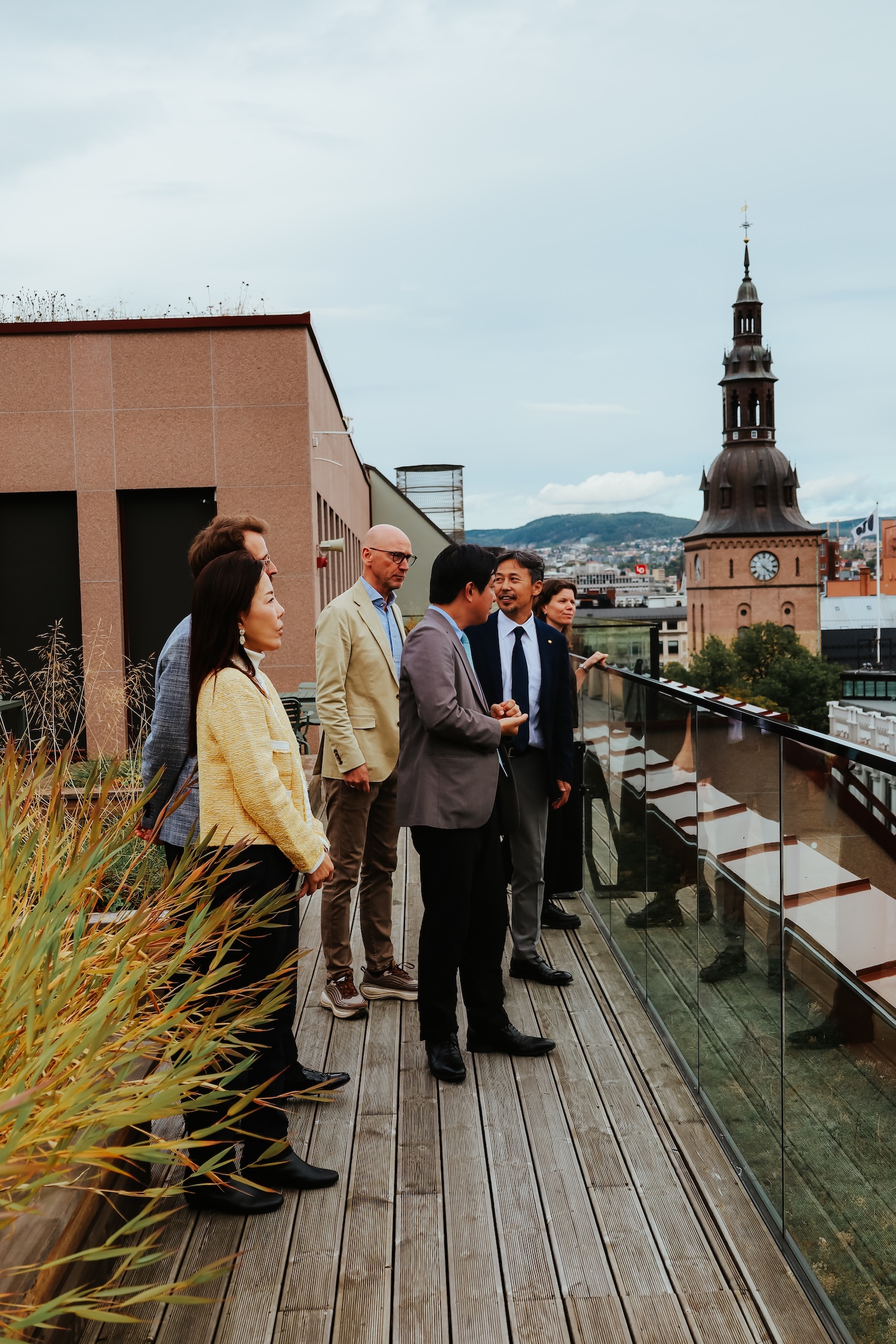 En liten gruppe mennesker oppe på en takterrasse med spiret til kirken i bakgrunnen