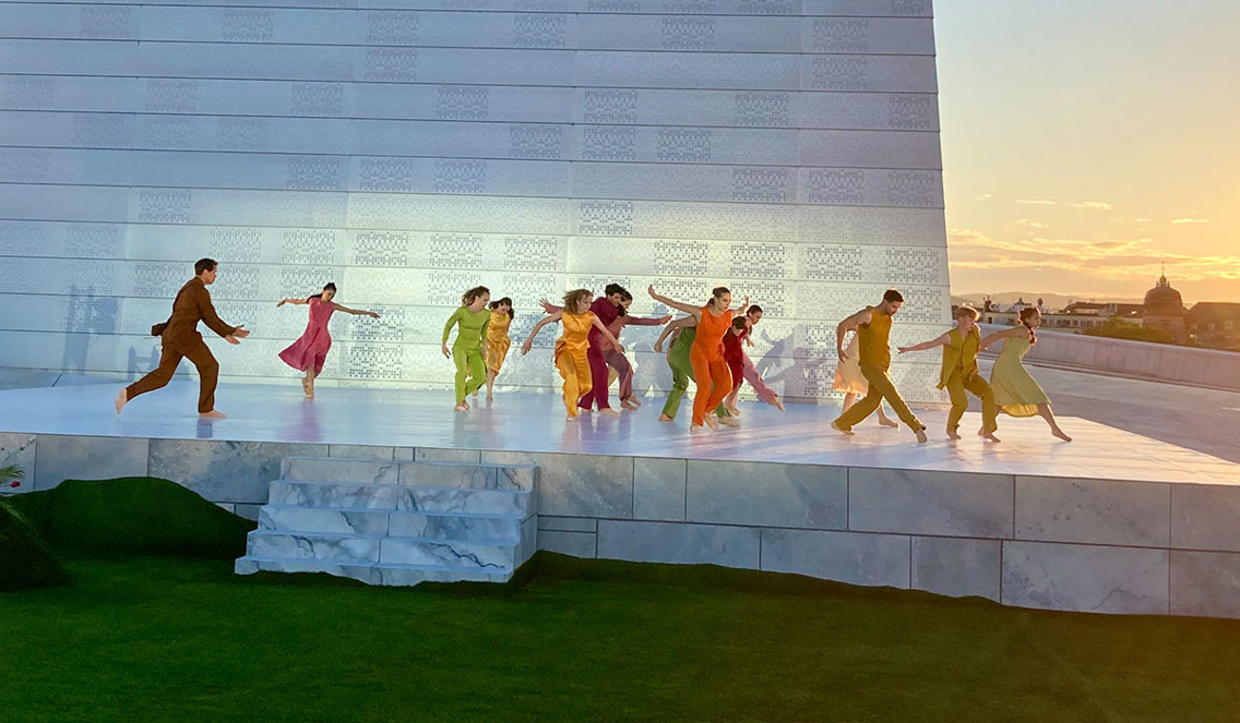 Danserer i flagrende, fargerike klær som løper på en marmorscene oppe på Operataket.