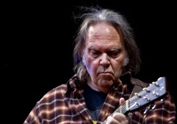 Neil Young på scenen med en gitar i hendene