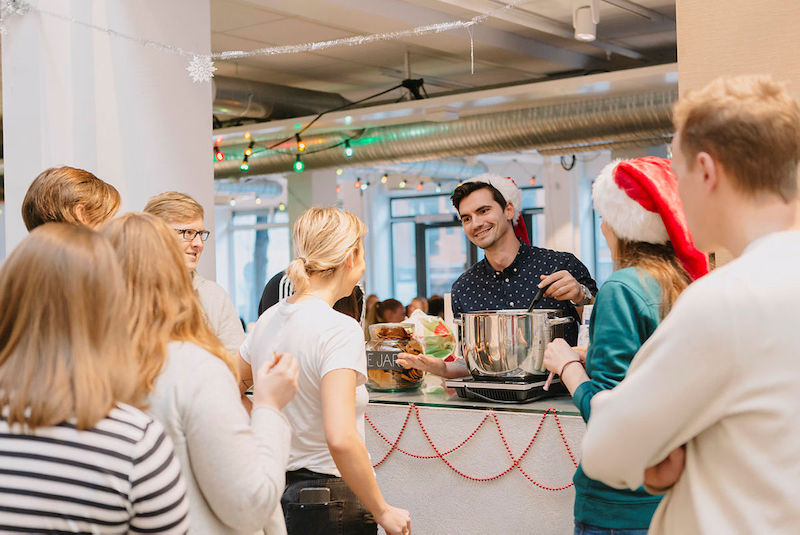 En ung mann serverer gløgg og peppekaker til studenter.