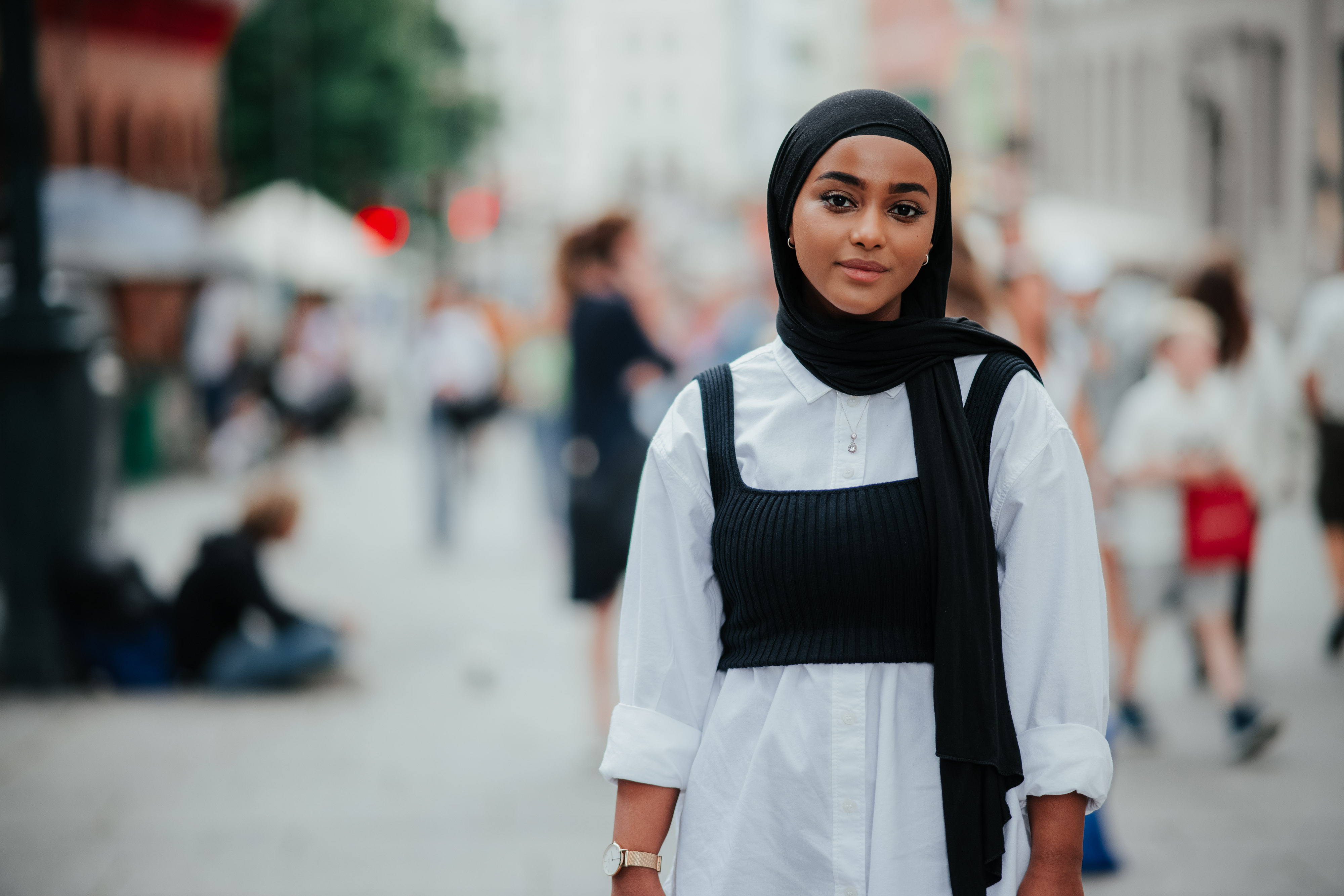Ung kvinne i lys skjorte og hijab poserer for kamera.