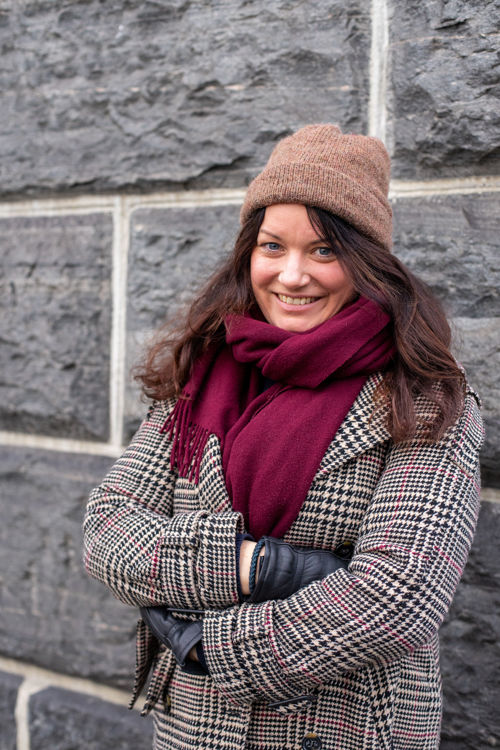 Foto av Ragnhild foran en murvegg.