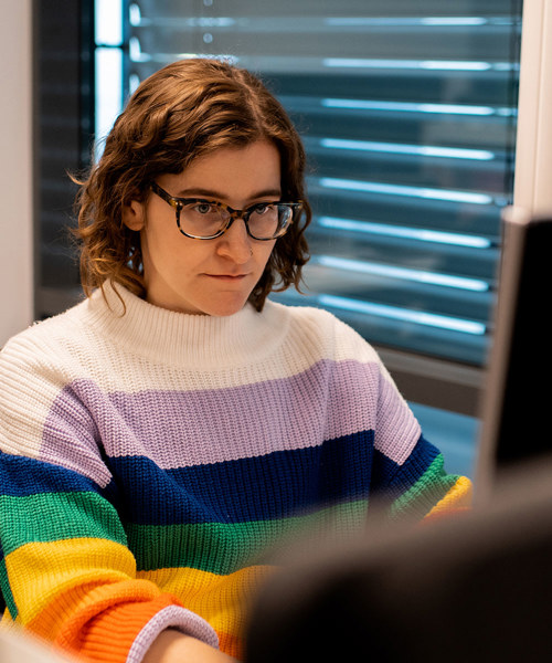 Foto av Stefanie Dziadkowiec som sitter ved kontorpulten sin og jobber.
