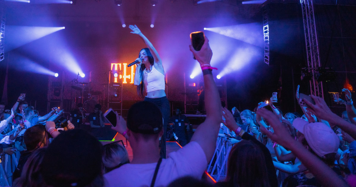 Konsert der vi ser artisten på scenen i lilla lys.