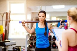 Kvinne på trening med en vektstang på skuldrene