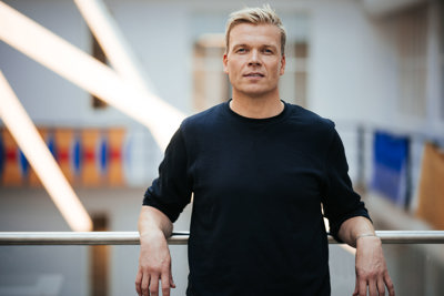 Mann i sort genser lener seg på et rekkverk.