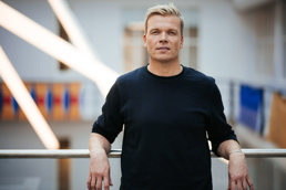 Mann i sort genser lener seg på et rekkverk.