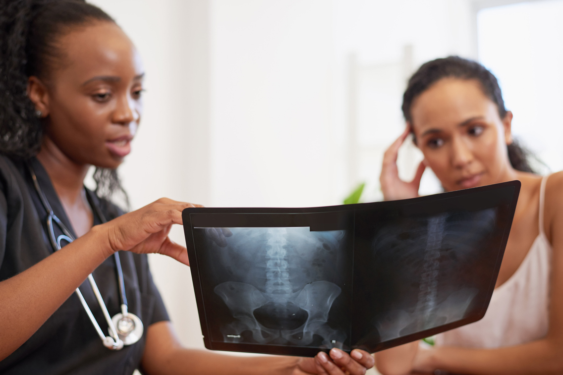 Kvinnelig doktor som snakker om bekken med kvinnelig pasient.
