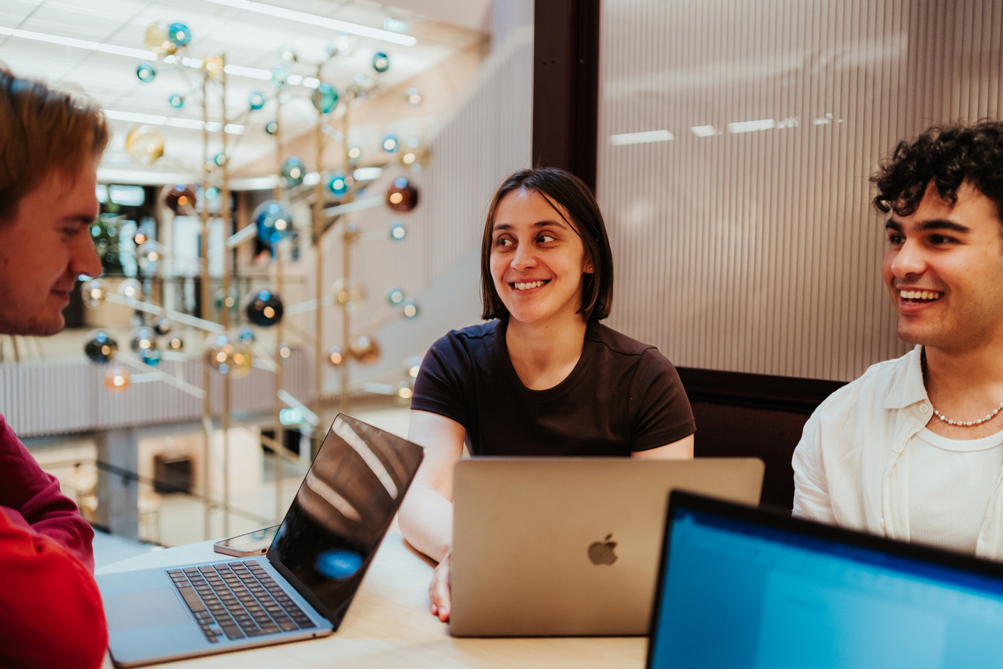 Tre studenter jobber i kollokvie med PC-er.