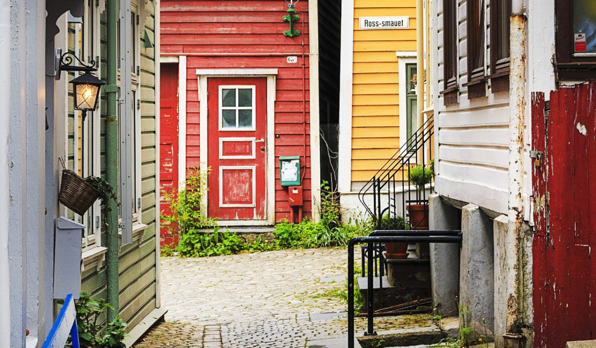 Bilde av noen hus i Bergen. Det ligger brostein på bakken.