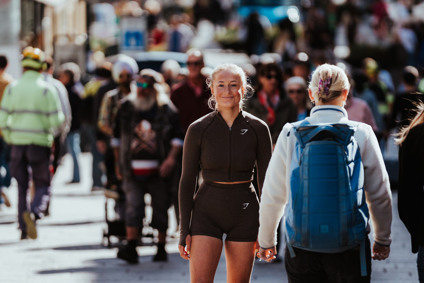 Kvinne i treningstøy står i en folkemengde og smiler mot kamera.