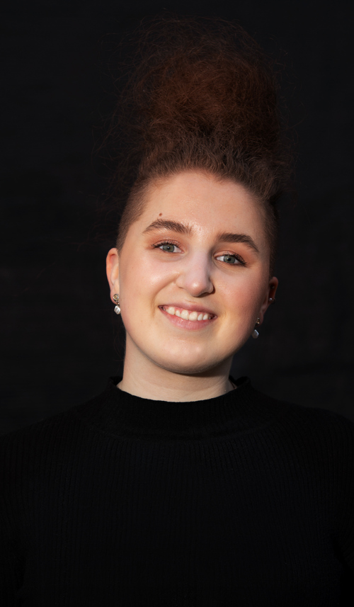 Portrett av Guro Kjensli Johansen , tidligere student i 3d og animasjon ved Fagskolen Kristiania. Guro har oppsatt hår, øredobber og en svart genser på seg.