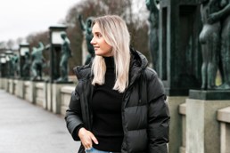 Ung blond kvinne i sort jakke ser utover frognerparken