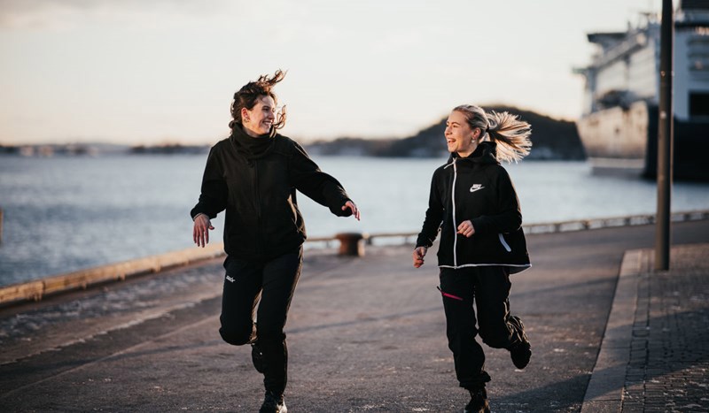 To kvinner som jogger langs en kai.