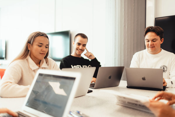 Studenter som sitter på Mac rundt et bord