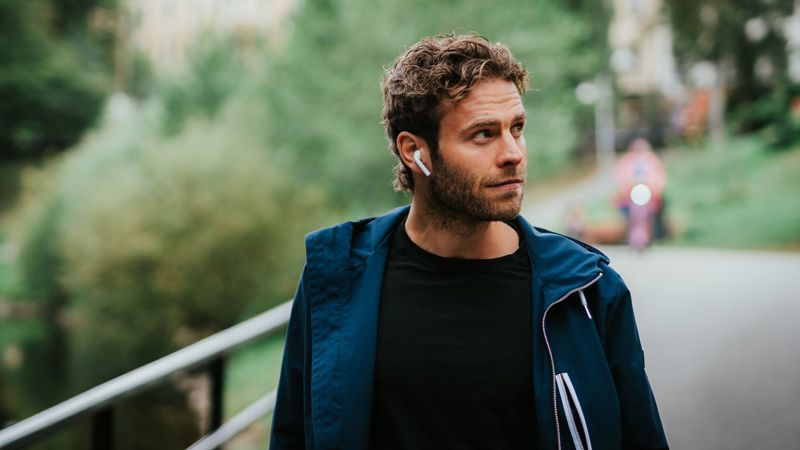 Mann går langs Akerselva i Oslo, og hører på nettundervisning med AirPods.