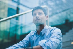 En mann i skjorte ser ut av et vindu